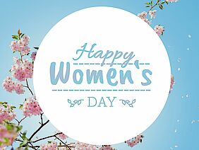 Schriftzug: Happy Women's Day mit blühender Zierkirsche im Hintergrund